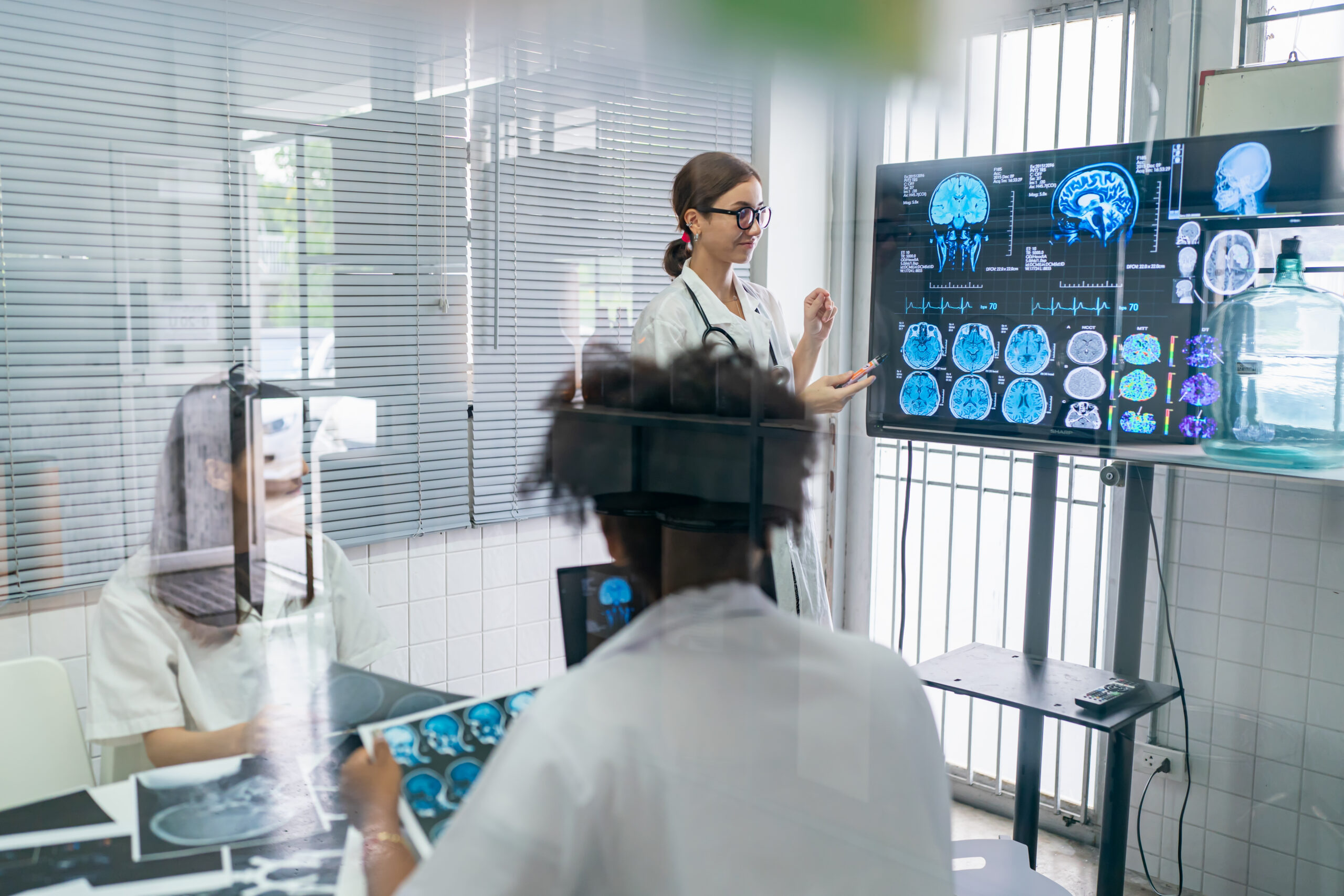 Team of doctors discuss results of X-Ray or MRI scan of patient's brain in medicine office of clinic